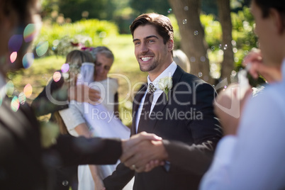 Groom shaking hand with guest in park