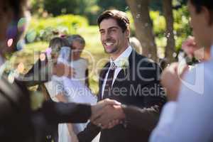Groom shaking hand with guest in park