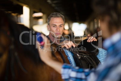 Man grooming the horse in the stable