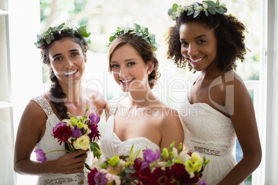 Bride and bridesmaids standing with bouquet at home