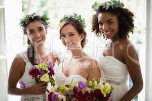 Bride and bridesmaids standing with bouquet at home