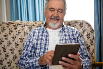 Smiling senior man using digital tablet in nursing home