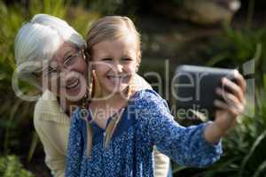 Grandmother and granddaughter taking selfie with mobile phone in garden