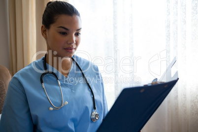 Female doctor reading reports while standing in nursing home