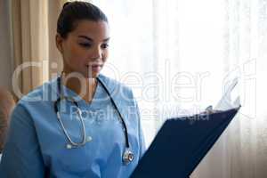 Female doctor reading reports while standing in nursing home