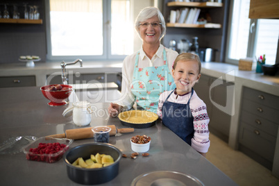 Smiling grandmother and granddaughter posing while making pie