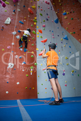 Trainer assisting boy in rock climbing