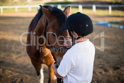 Rider boy caressing a horse in the ranch