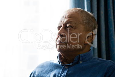 Close up of senior man looking away while sitting by window