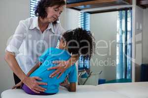 Physiotherapist giving back massage to girl patient