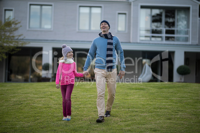 Father and daughter holding hands and walking in the garden