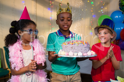 Children looking at cake held by boy
