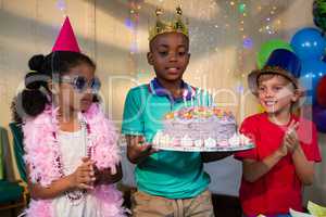 Children looking at cake held by boy