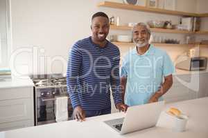 Smiling father and son standing together in kitchen