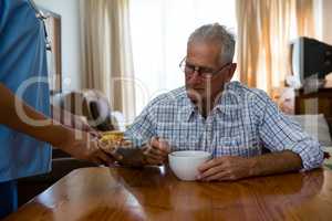 Female doctor serving food to senior man in nursing home