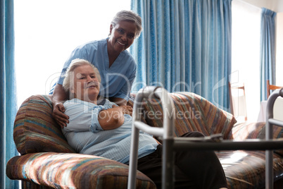 Smiling nurse with senior woman at sofa in nursing home