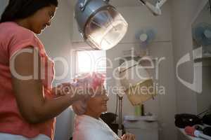 Side view of beautician adjusting curlers on senior woman hair