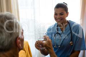 Female doctor giving water to senior man