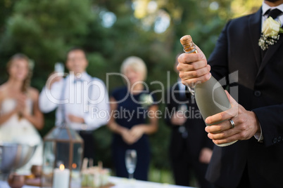 Groom opening champagne bottle at park