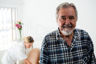 Portrait of senior man with female doctor in background