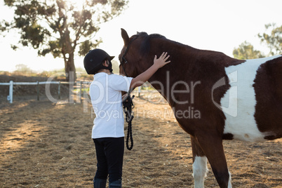 Rider boy caressing a horse in the ranch