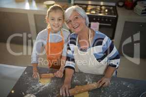 Grandmother and granddaughter posing while flattening dough