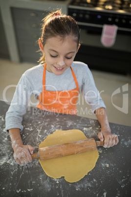 Little girl flattening dough on the kitchen counter