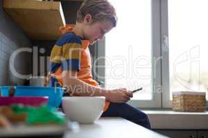 Boy using digital tablet at kitchen counter