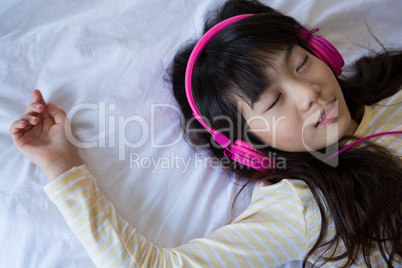 Girl listening to music while relaxing on bed