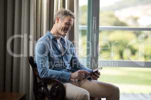 Smiling man using digital tablet on chair