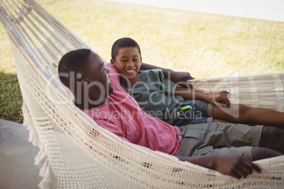 Smiling father and son relaxing on a hammock