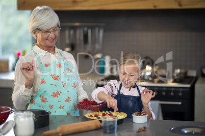 Grandmother and granddaughter adding strawberries to the crust