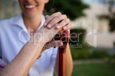 Cropped hands of female doctor and woman holding walking cane