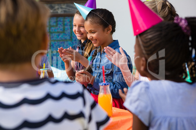 Children applauding while sitting at table