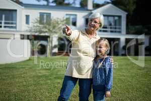 Grandmother and granddaughter pointing in the garden