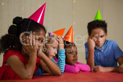 Tired children wearing party hat at table