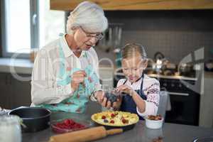 Grandmother and granddaughter adding blue berries to the crust