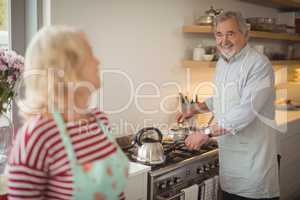 Senior couple preparing food while interacting in kitchen