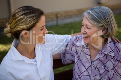 High angle view of senior woman talking to doctor while sitting on bench