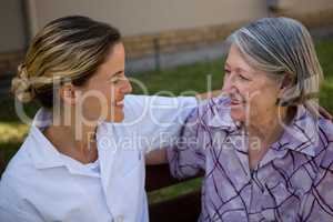 High angle view of senior woman talking to doctor while sitting on bench