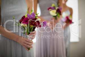 Bride standing with flower bouquet at home