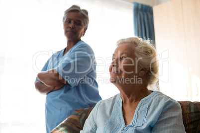 Nurse looking at thoughtful patient relaxing on sofa