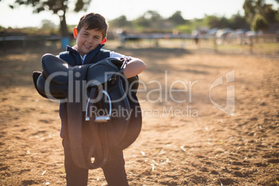 Boy holding horse saddle