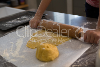 Cropped hands of boy rolling dough
