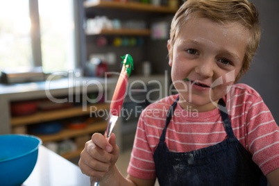 Portrait of boy holding spatula with batter