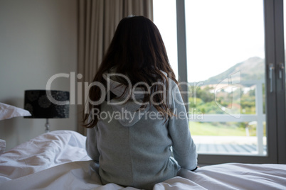 Rear view of girl sitting on bed