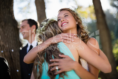 Bride embracing her friend in park