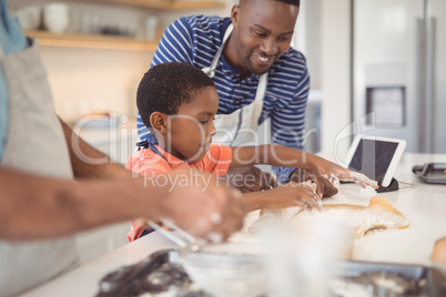 Boy preparing cookie dough with his father and grandfather in kitchen