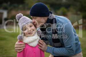 Father kissing her daughter in garden