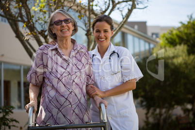 Portrait of senior woman holding walker standing with doctor